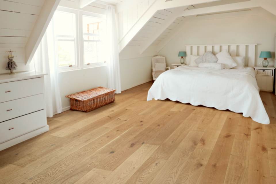 light hardwood flooring in bedroom with white bedding and white walls